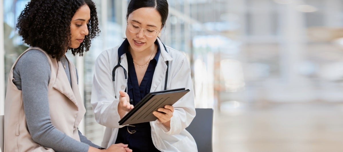 5 Benefits of Epidural Back Injections-3-Doc A doctor in a lab coat points to a clipboard and talks to a patient about epidural back injections