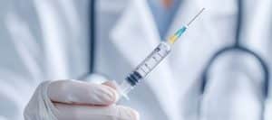 A doctor in a lab coat holds a needle used for epidural back injections