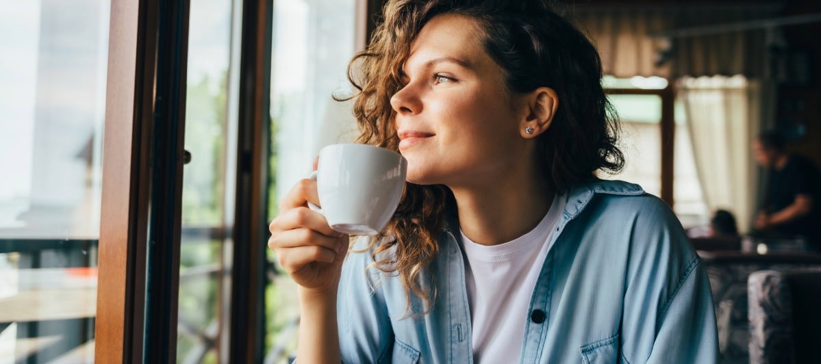 5 Benefits of Epidural Back Injections-4-Coffee A woman smiles and holds a cup of coffee after epidural back injection treatment