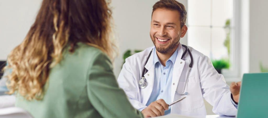 A doctor in a lab coat smiles as he talks to a patient about platelet rich plasma treatment