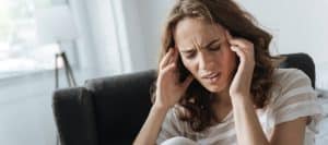 A woman grabs her head in pain from a migraine headace