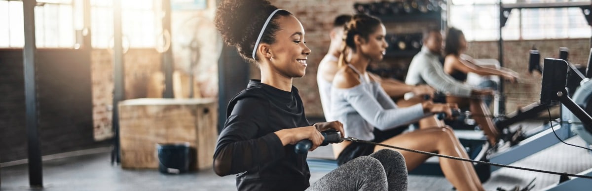 5 Facts About Glucose Monitoring Implants You Should Know-10 A woman smiles as she exercises on a rowing machine after receiving glucose monitoring implants