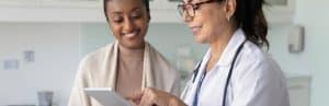 A doctor in a lab coat talks to a smiling patient about glucose monitoring implants