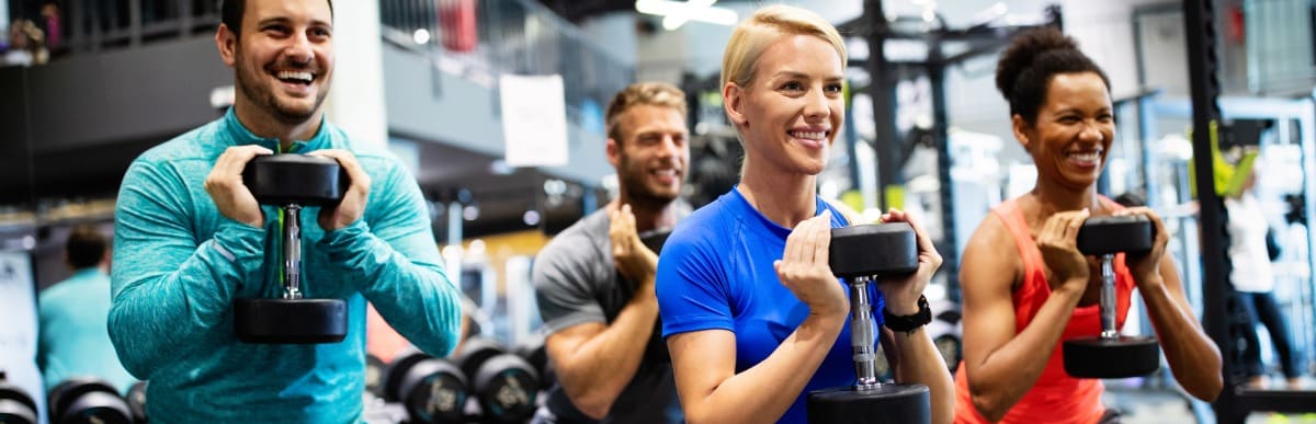 5 Facts About Glucose Monitoring Implants You Should Know-8 A woman smiles as she lifts a weight in a gym after receiving glucose monitoring implants