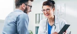 A doctor in a lab coast smiles as she tells a patient about amino acid treatment