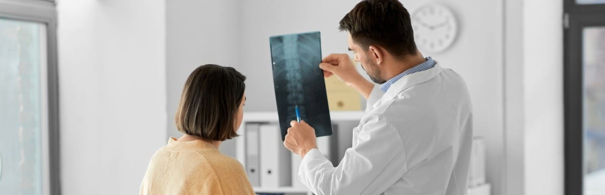 5 Types of Back Pain You Should Know-4 A doctor points to an X-ray and talks about different types of back pain with a patient