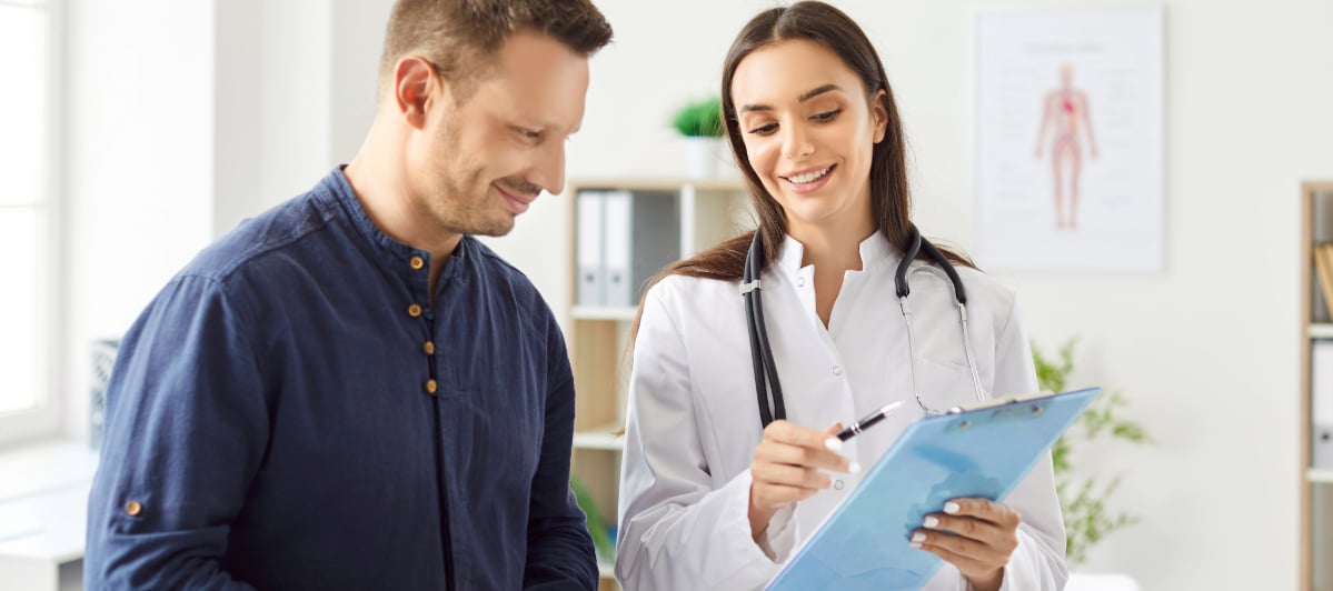 A Guide to Chronic Pelvic Pain Causes and Treatments-5-Diagnosis A doctor points to a clipboard and talks to a patient about chronic pelvic pain