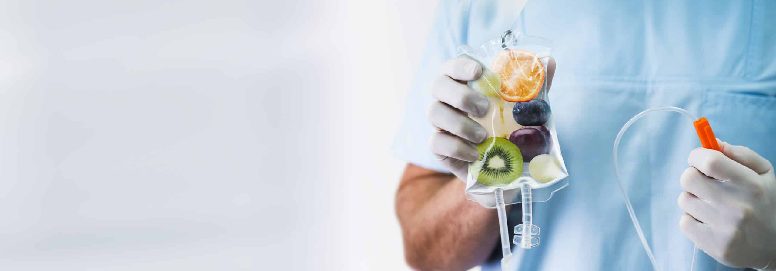 Doctor Holding Saline Bag With Fruit Slices Inside In Hospital IV Drip Vitamin Infusion Therapy Bag Held By Doctor