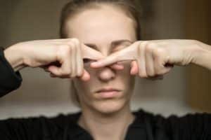 A young woman touches her nose because she loss of her sense of smell, does not feel the smell. Anosmia