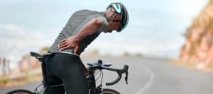 A bicyclist holds his back in pain before facet joint injection treatment