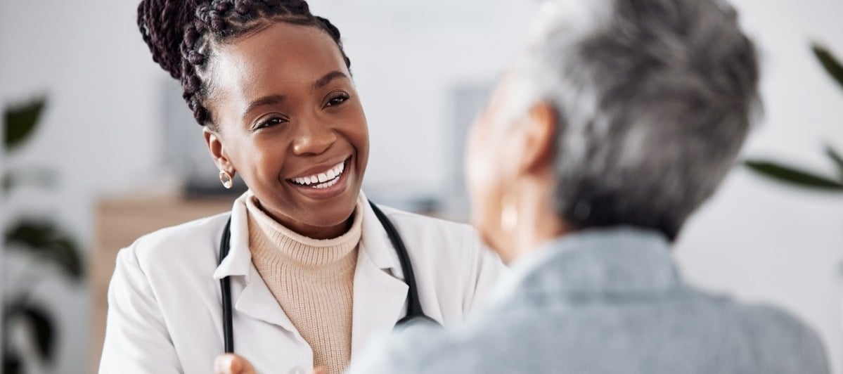 Are Facet Joint Injections Right for Your Back Pain-6 A doctor in a lab coat smiles as she talks about facet joint injections with her patient