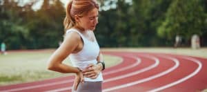 A runner winces and holds her back in pain before lumbar epidural injection treatment