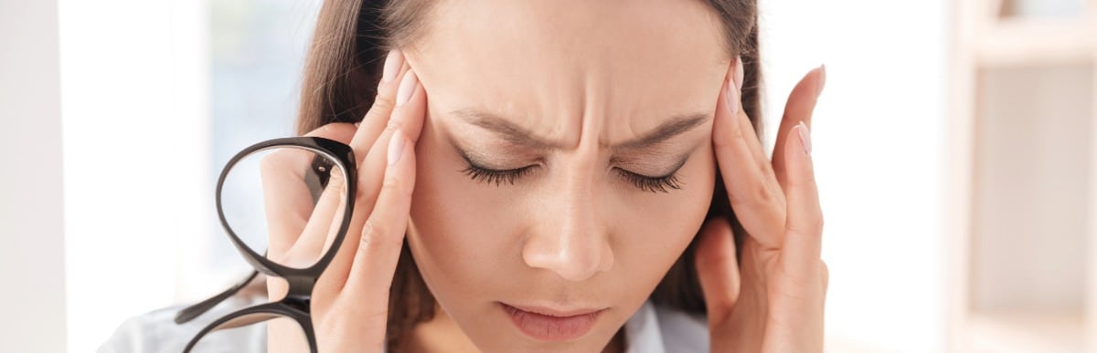 Can Hormone Replacement Help Hair Loss-3 A woman winces with a headache and touches her temples due to hair loss
