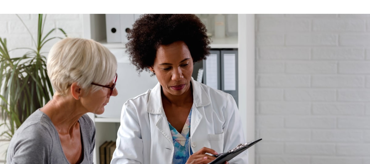 Can Weight Loss Injections Reduce Chronic Pain-7-Doctor and patient A doctor holds a clipboard and reads information about how weight loss injections can ease chronic pain
