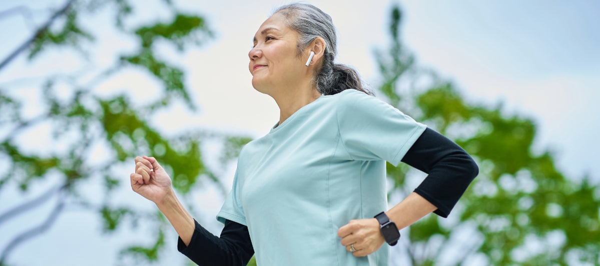 An older woman smiles as she jogs to ease symptoms of diabetic neuropathy