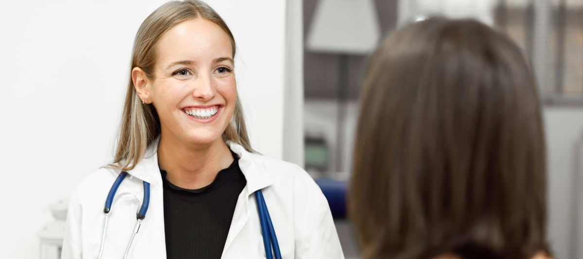 Common Questions About Trigger Injections-4-Doc A doctor in a lab coat smiles as she discusses trigger injections with a patient