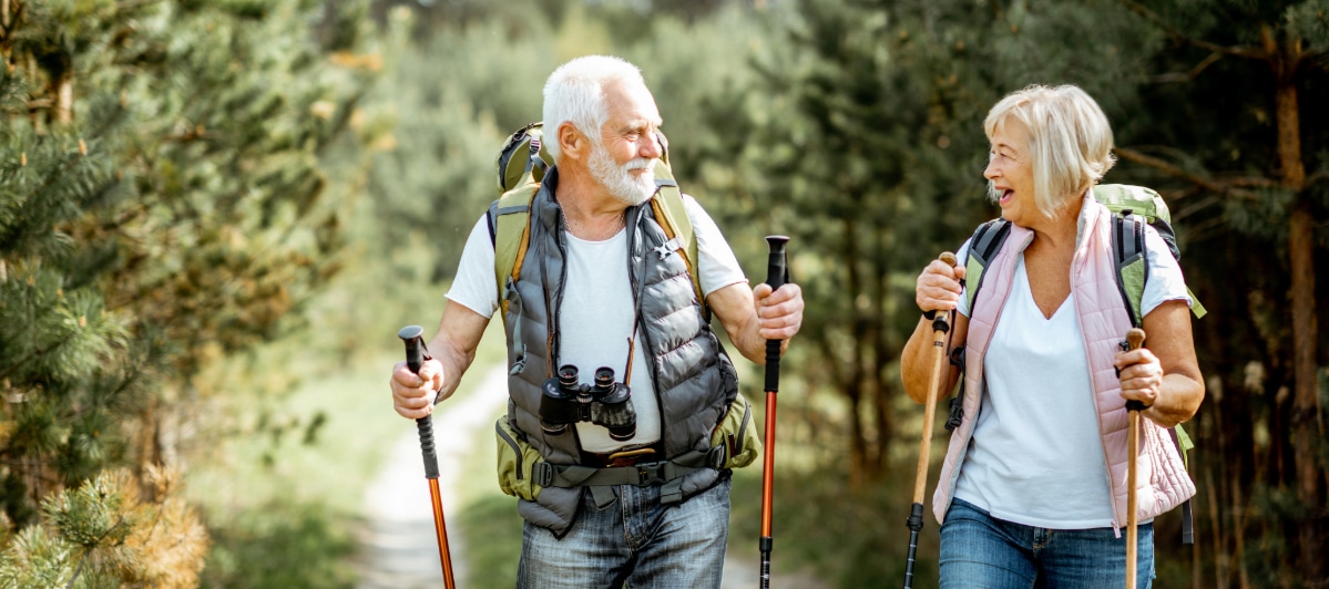 Common Questions About Trigger Injections-5-Hikers Two older hikers wearing backpacks smile as they hike on a trail