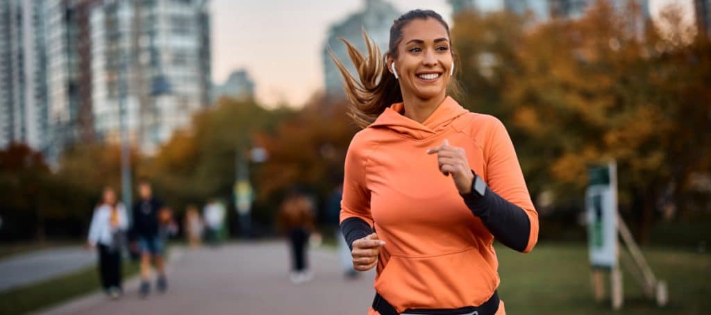 A woman smiles as she jogs after hormone replacement therapy