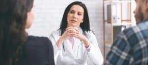 A doctor in a lab coat talks to her patients about hormone replacement therapy