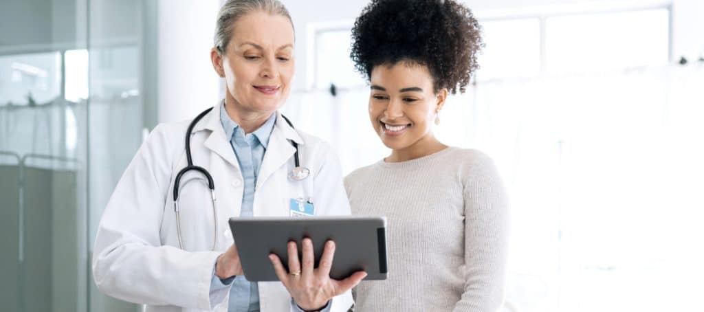 A patient smiles as her doctor explains the benefits of photobiomodulation