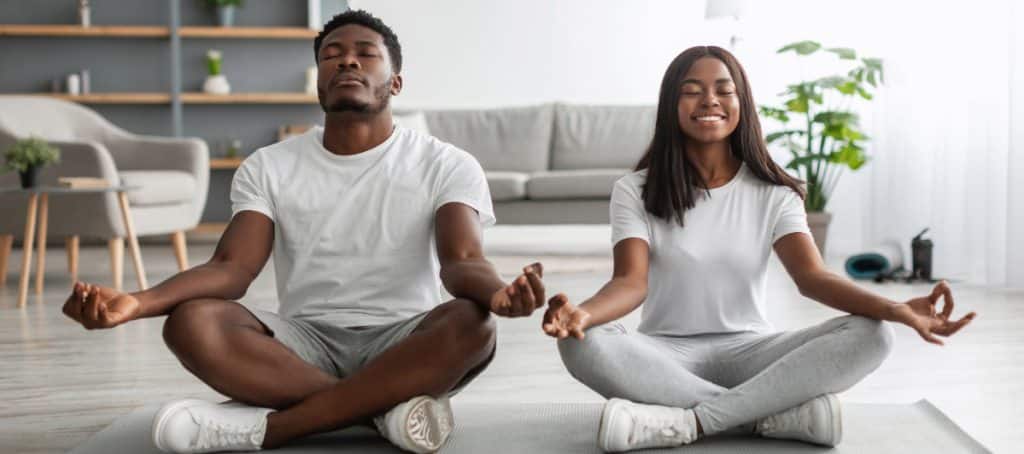 A man and woman sit cross-legged and meditate