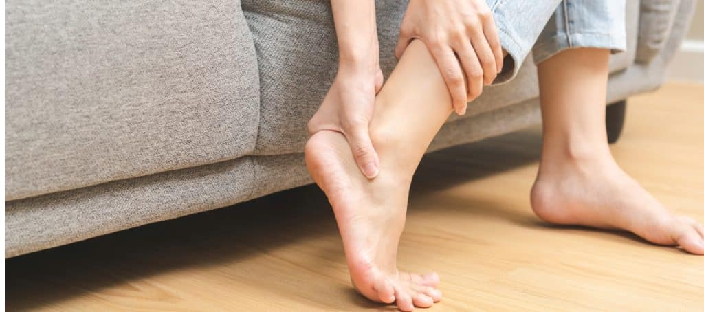 A person grabs her foot in pain due to diabetic peripheral neuropathy