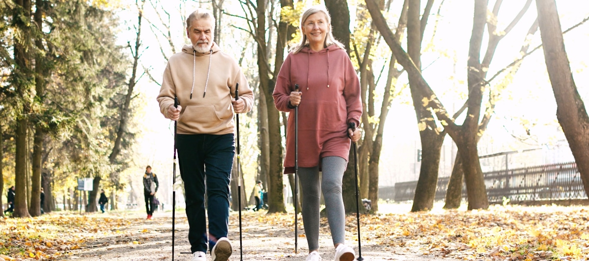 Effective Pain Relief Strategies for Spinal Stenosis-4-Walkers Two people smile as they walk through a park for exercise to combat the effects of spinal stenosis