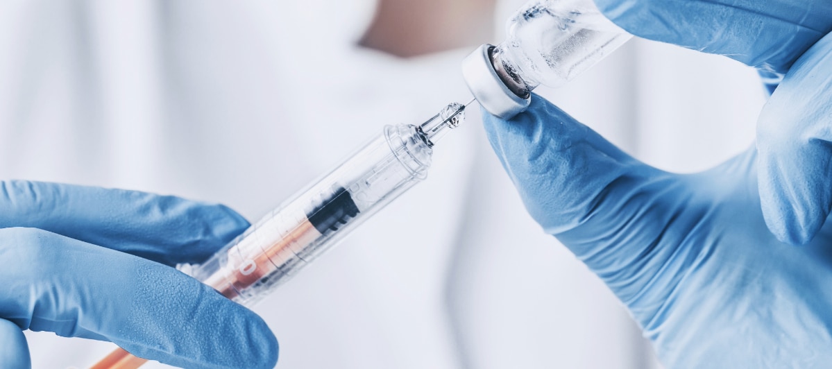Effective Pain Relief Strategies for Spinal Stenosis-5-Injection A doctor with exam gloves on withdraws a plunger on an injection needle as a treatment option for spinal stenosis