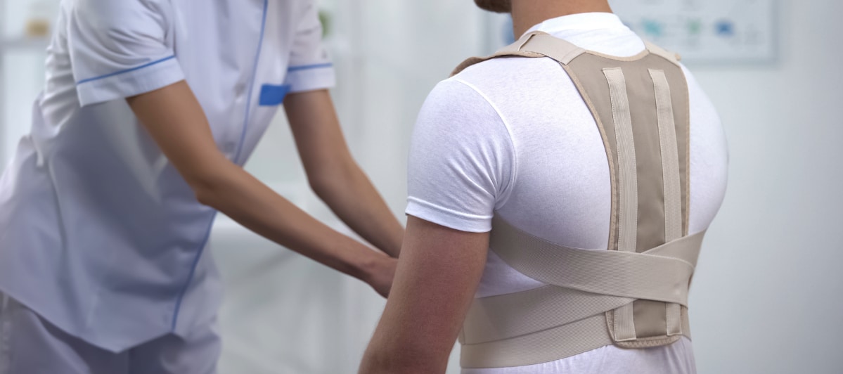 Effective Pain Relief Strategies for Spinal Stenosis-7-Brace A physical therapist helps a patient put on a back brace to ease pain from spinal stenosis