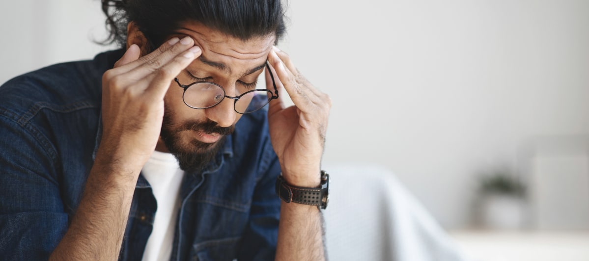 Explore 5 Symptoms of Middle Back Pain-4-Headache A man holds his head due to a headache from middle back pain
