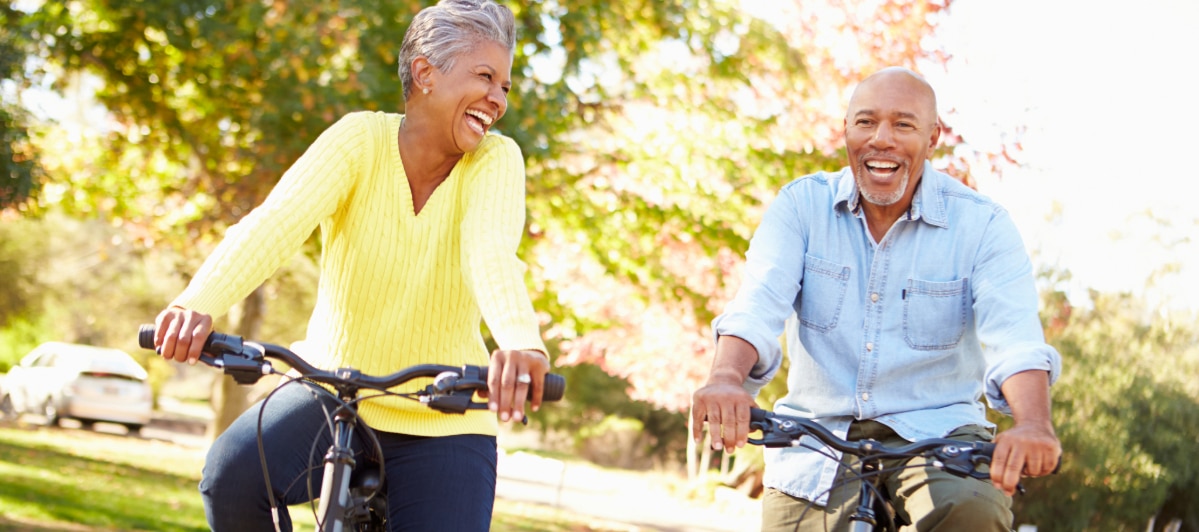 Explore 5 Symptoms of Middle Back Pain-6-Bikers A man and woman laugh as they ride bikes after treatment for middle back pain
