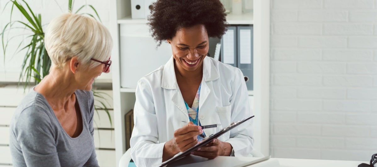 Exploring Minimally Invasive Treatments for Injuries-6-Doctor Patient A doctor smiles as she reviews minimally invasive treatments for injuries