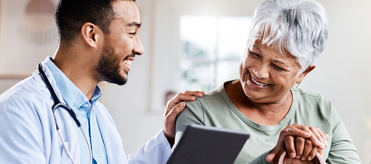 Exploring Minimally Invasive Treatments for Injuries-7-Smiling Doctor A doctor smiles and puts his hand on his patient's shoulder