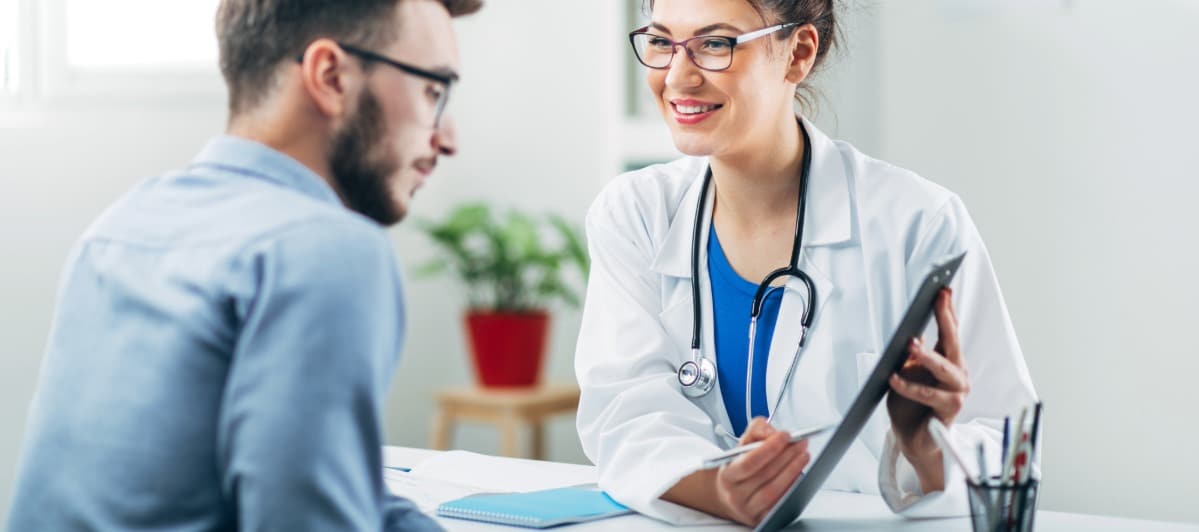 Exploring Neurostimulation Devices and Treatments-2-Doc A doctor in a lab coat smiles as she points to a clipboard and explains types of nerve stimulators to a patient