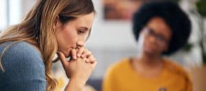 A woman holds her hand to her face during a therapy session for complex post-traumatic stress disorder