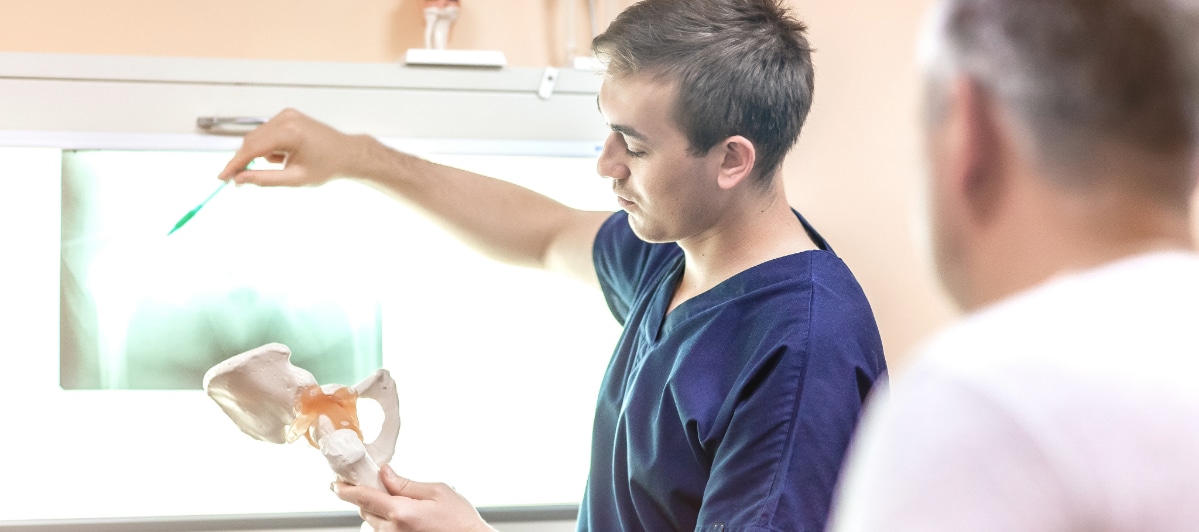 FAQs About Sacroiliac Joint Treatments for Hip Pain-3-Hip Doc A doctor uses a hip bone model and X-ray to describe hip fusion surgery