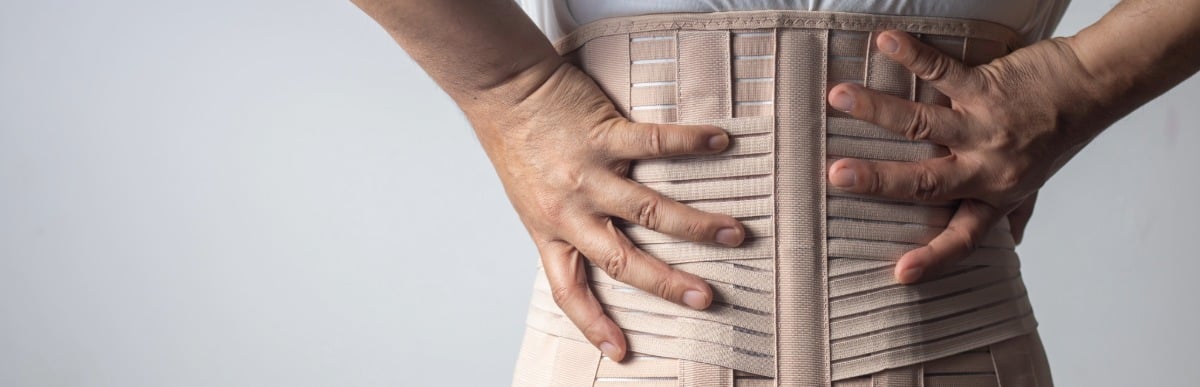 Heart Disease Symptoms You Need to Know (10) A person wears a back brace for middle back pain relief