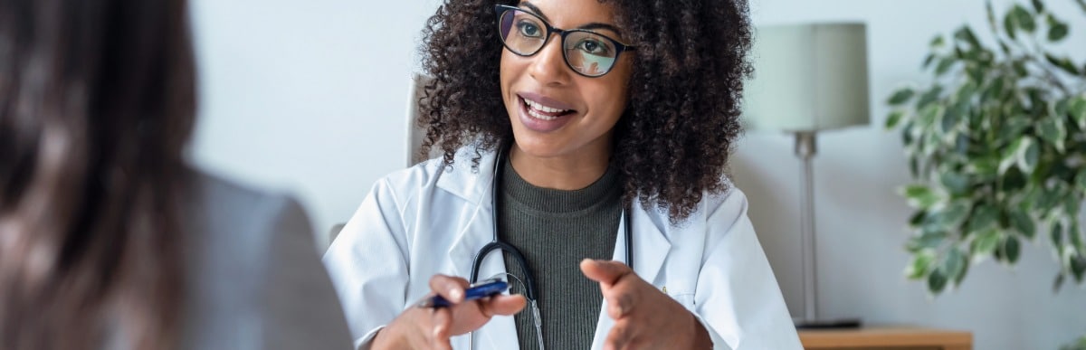 Heart Disease Symptoms You Need to Know (100) A doctor in a lab coat discusses hormone imbalance treatment with her patient