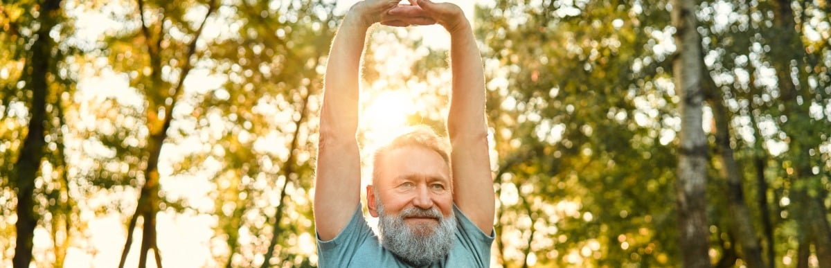 Heart Disease Symptoms You Need to Know (19) A man smiles and stretches his arms over his head to ease upper middle back pain