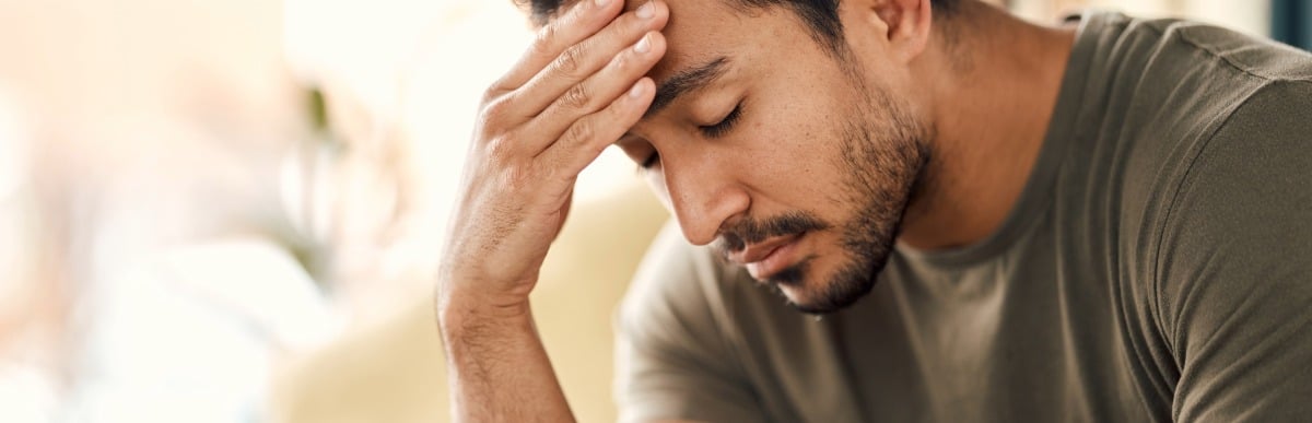 Heart Disease Symptoms You Need to Know-2 A man holds his hand to his head as he feels fatigue, one of the main heart disease symptoms