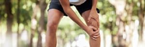 A runner, who is a candidate for platelet rich plasma therapy, holds his knee due to osteoarthritis
