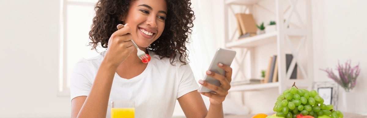 Heart Disease Symptoms You Need to Know - 2026-06-10T115540.778 A woman smiles as she checks her phone and eats a leafy green salad