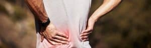 A runner holds his back due to inflammation from hormones and pain