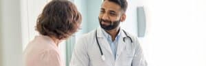 A doctor in a lab coat listens to to a patient ask about functional rehabilitation