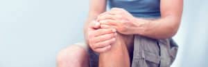A man holds his knee due to joint pain before * functional rehabilitation