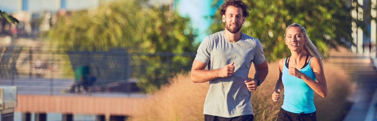 A man and woman smile as they jog with renewed energy after Emsculpt Neo treatment