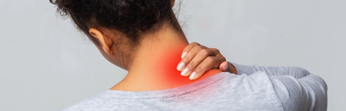 Heart Disease Symptoms You Need to Know (25) A woman holds the back of her neck due to radiating upper back pain