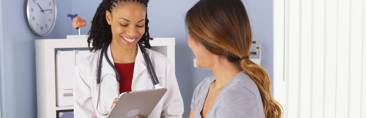 Heart Disease Symptoms You Need to Know (29) A doctor in a lab coat smiles as she tells a patient about treatments for upper back pain