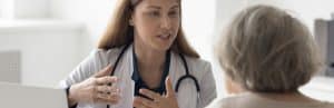 A doctor in a lab coat tells her patient about the lumbar epidural injection procedure