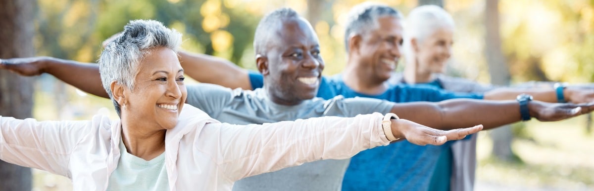 Heart Disease Symptoms You Need to Know (35) People in a yoga class smile as they hold a pose with their arms